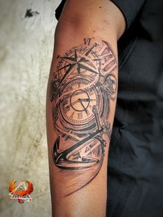 a man's arm with a clock and compass tattoo design on the left upper arm