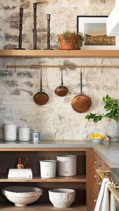 pots and pans are hanging on the wall above the kitchen counter, along with other utensils