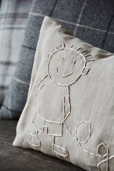 a pillow with a drawing on it sitting on top of a couch next to pillows