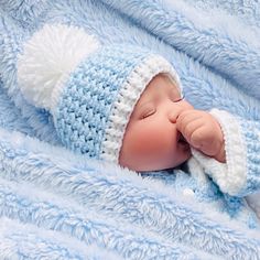 a baby wearing a blue and white knitted hat laying on top of a blanket