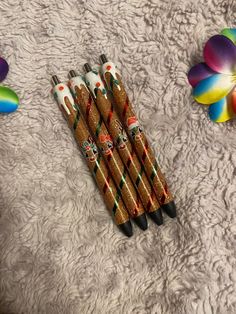 four pens are lined up next to each other on a white surface with flowers in the background