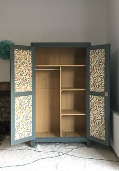 an open cabinet with painted doors and shelves