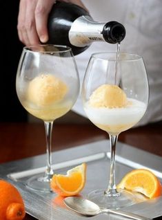 a person pouring orange juice into two wine glasses