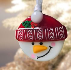 a glass ornament with a snowman's hat hanging from the top