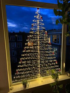 a lit up christmas tree sitting on top of a window sill