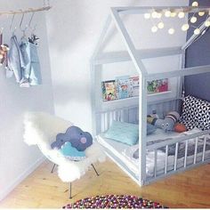 a child's room with a bed, chair and toys hanging from the ceiling