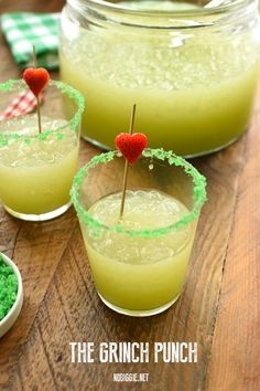 three glasses filled with green liquid and topped with strawberries on the rim, sitting on a wooden table