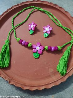 a pink plate with green tassels and purple flower decorations on it's side