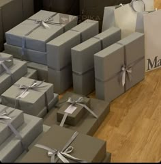 many gray boxes with silver ribbons and bows on them are sitting on the floor next to each other