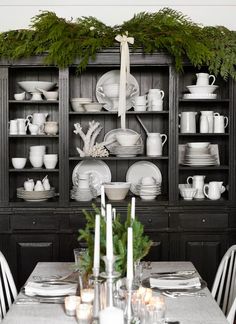 the dining room table is set with white dishes and place settings for dinner party guests