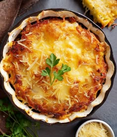 a casserole dish with cheese and parmesan on top, next to two small bowls