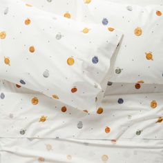 an image of a bed with white sheets and colorful polka dot print on the covers