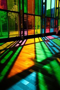 the sun shines through windows in an empty room with wooden floors and colorful walls