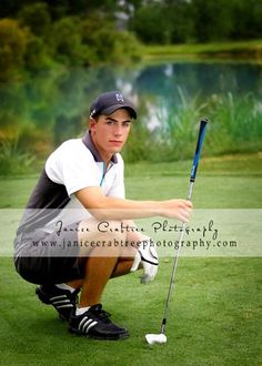 a young man kneeling down on top of a green field holding a golf racquet