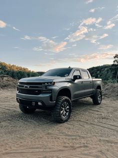 a silver truck is parked in the dirt