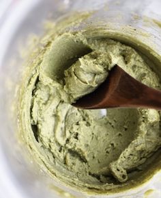 a wooden spoon in a mixing bowl filled with green food coloring and batter on the side