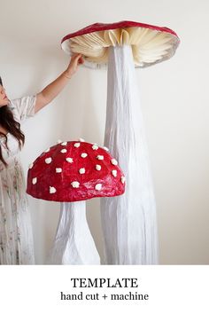 a woman is holding up a paper mache mushroom