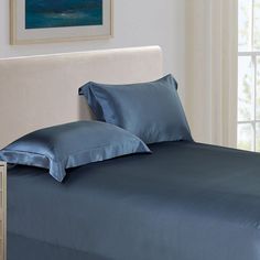 a bed with blue sheets and pillows in a room