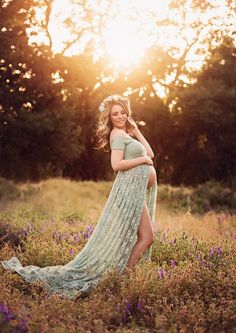 a pregnant woman poses in a field at sunset