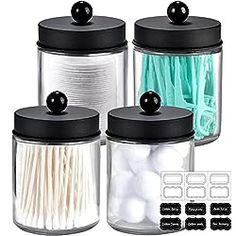 four glass jars with black lids and white cotton swabs