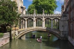 people on small boats in the water under a bridge with arched windows and stone architecture