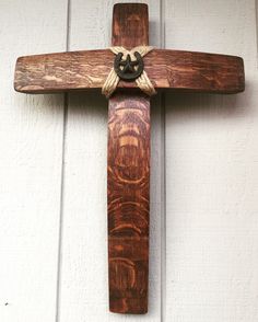 a wooden cross hanging on the side of a white building with a knot around it