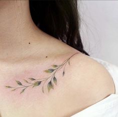 a woman's chest with green leaves tattoo on her left shoulder and right breast