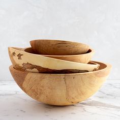 three wooden bowls stacked on top of each other in front of a marble countertop