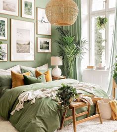 a bedroom with green walls and pictures hanging on the wall above the bed, along with a wicker basket