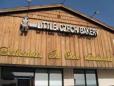 a little czech bakery is located on the side of a building with wooden siding and windows