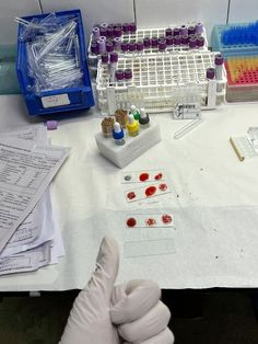 a gloved hand is pointing at some samples on a table