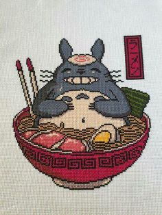 a cross stitch picture of a totoro eating ramen with chopsticks