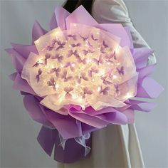 a woman is holding a bouquet with lights in it