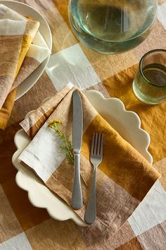 an empty plate and silverware on a checkered table cloth