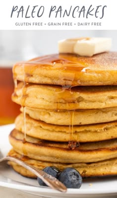 a stack of pancakes with butter and blueberries on a white plate next to syrup