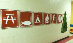 several red signs mounted to the side of a white wall in a school hallway next to a christmas tree