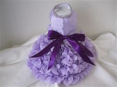 a dress made out of purple flowers on a white cloth with a purple ribbon around the waist