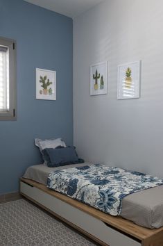 a bed sitting in a bedroom next to two pictures on the wall and a window