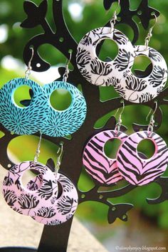 four pairs of earrings are hanging from a metal tree with zebra print designs on it