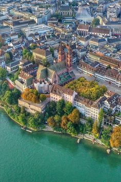 an aerial view of a city next to the water with buildings and trees around it