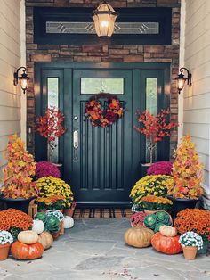 the front door is decorated with fall foliage and pumpkins