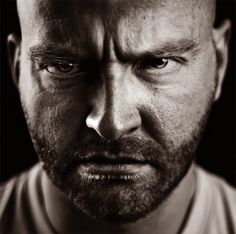 a black and white photo of a man with a bald head looking at the camera