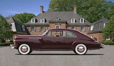 an old car is parked in front of a large house