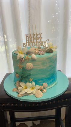 a birthday cake decorated with seashells and flowers