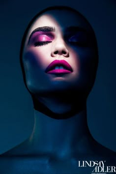 a woman's face is lit up with blue and pink makeup