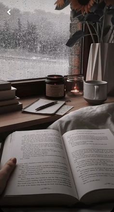 an open book sitting on top of a table next to a window