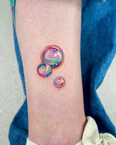 a woman's ankle with three bubbles on it and one is pink, blue, green, yellow or red