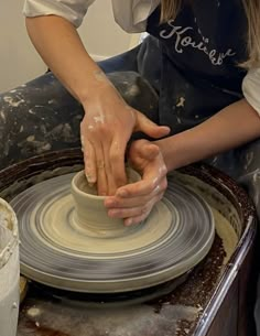 a woman is making a bowl on a potter's wheel with her hands in it