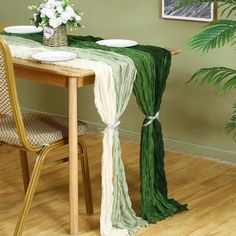 the table is set with plates and napkins on it, near a potted plant