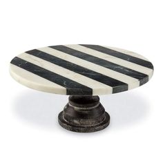 a black and white striped cake plate on an iron stand with marble top, in the shape of a pedestal